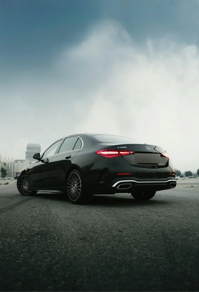 A black executive saloon parked under a cloudy sky