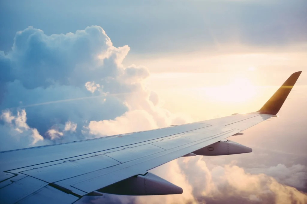 The wing of a plane above the clouds at sunrise