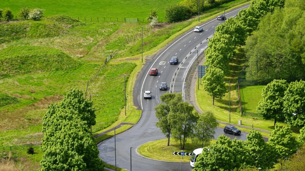 Cars on a winding dual carriageway through green countryside