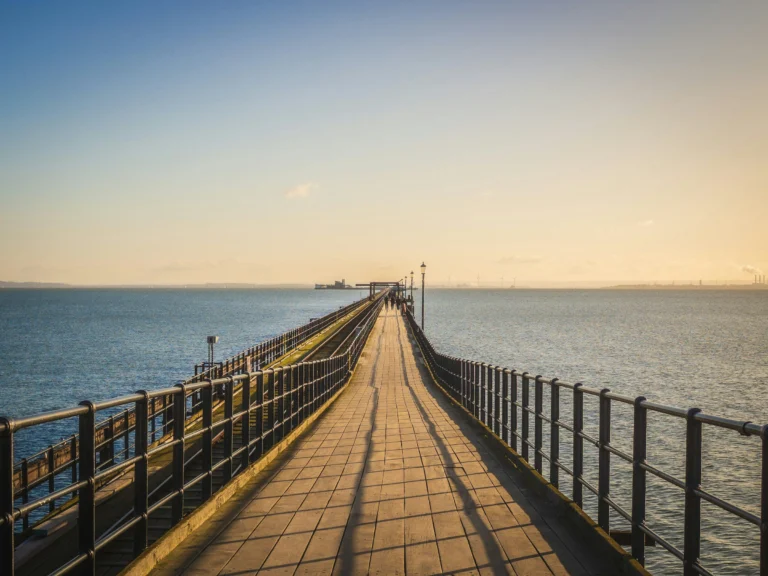 A long wooden pier stretching out over calm water in the evening sun
